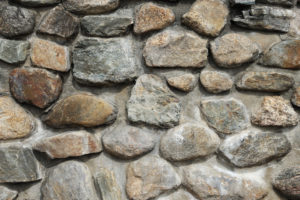 close up rock wall fence with large rocks and cement