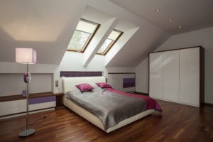 a remodeled home bedroom with a large bed and sky lights