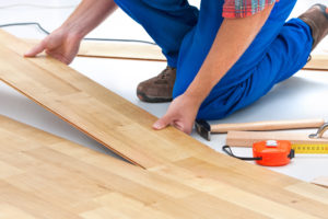 construction worker laying down planks of wood for flooring