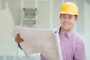 happy construction contractor holding plans inside a house he's adding onto 