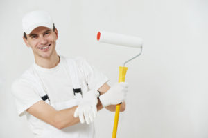 smiling professional painter in a white room holding a paint roller