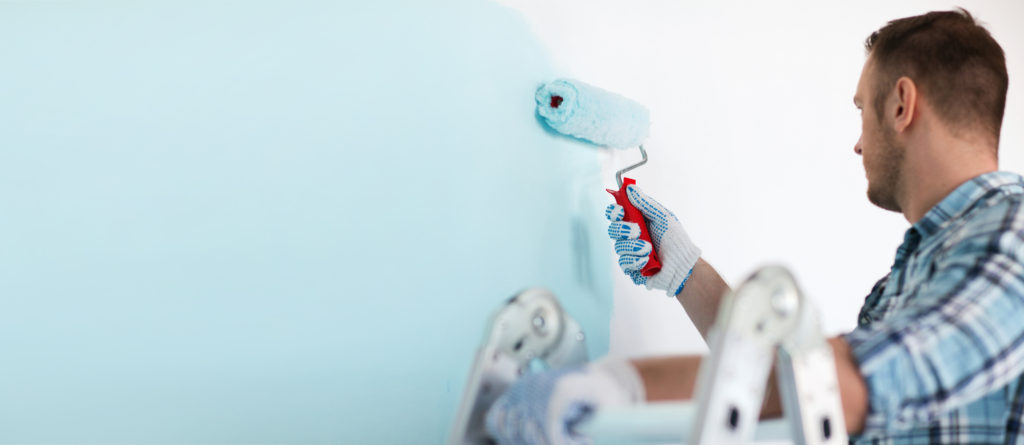 a commercial painter painting a white wall baby blue